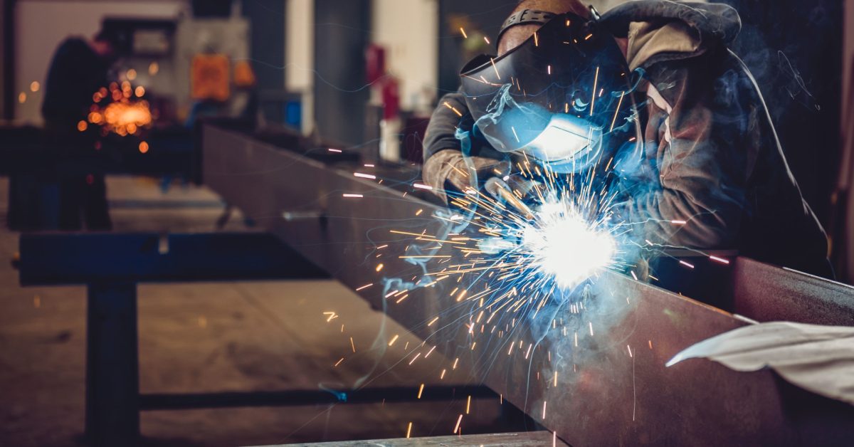 Hitsaaja työssä metallipajassa kipinöiden keskellä
